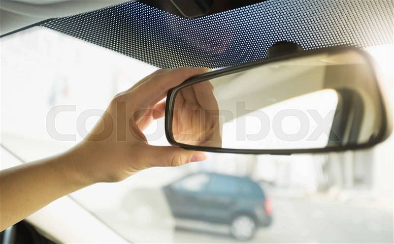 Closeup photo of driver adjusting rear view mirror, stock photo