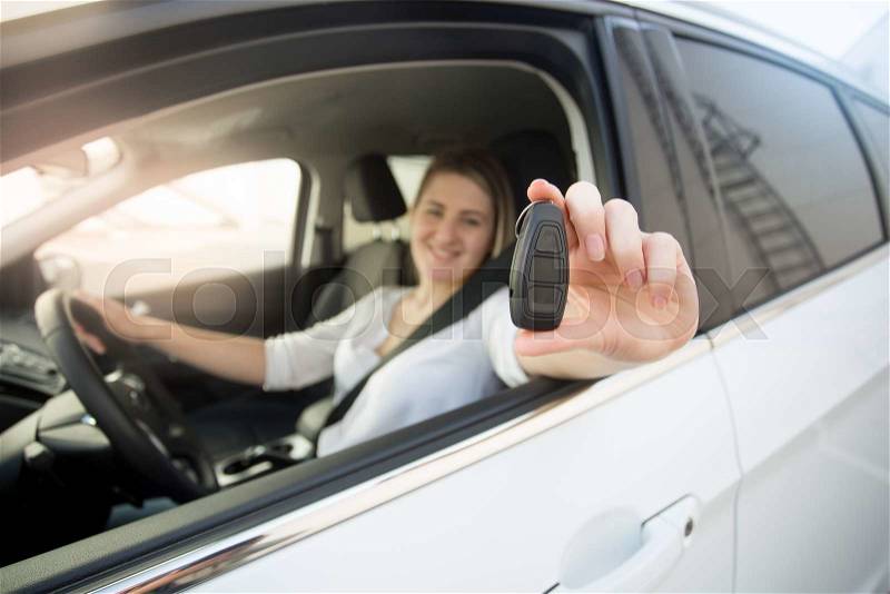 Closeup of female driver showing car keys through open window, stock photo