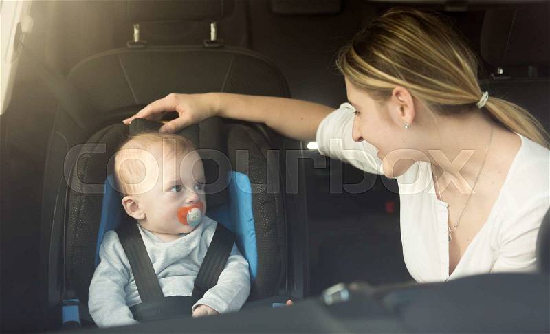 Happy young mother and baby in car child seat, stock photo
