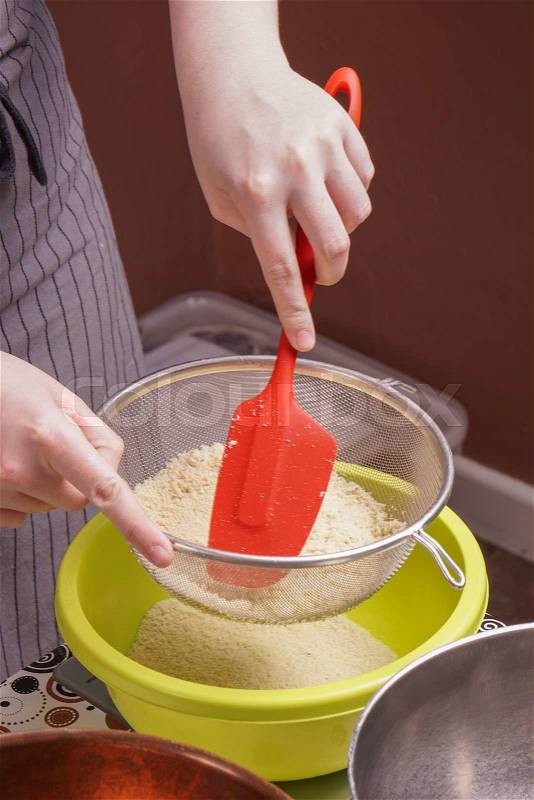 Hands sifts flour in to a bowl for cake baking, stock photo
