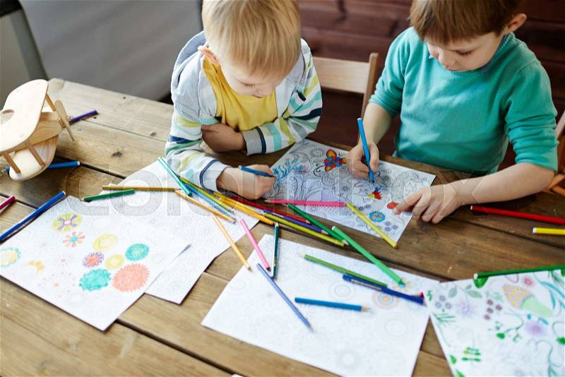 Adorable siblings coloring pictures with highlighters, stock photo
