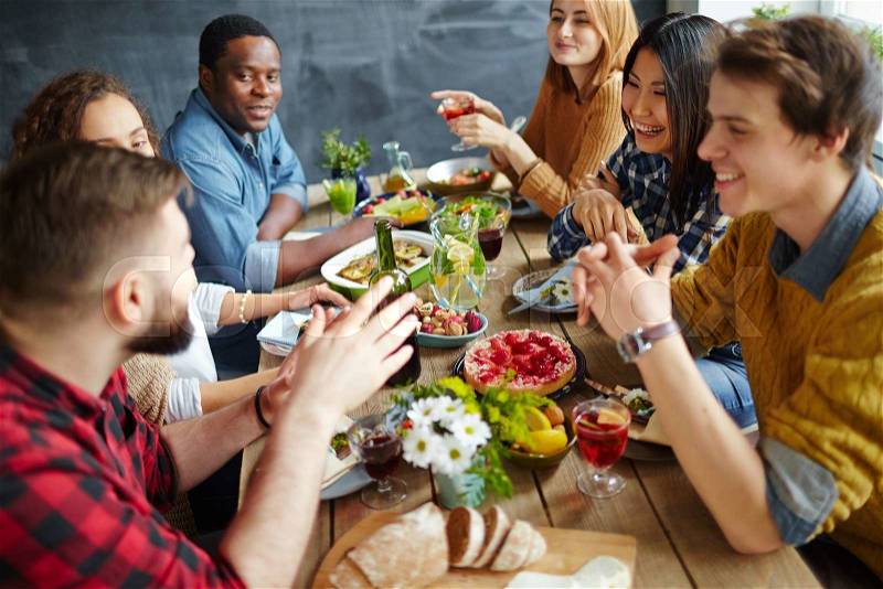Group of happy friends having conversation by festive dinner, stock photo