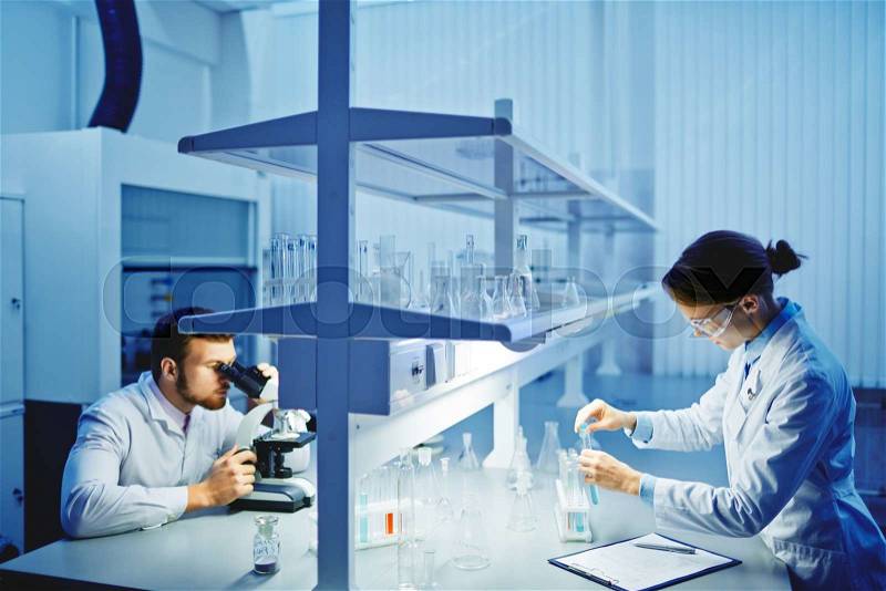 Young clinicians studying substances in lab, stock photo