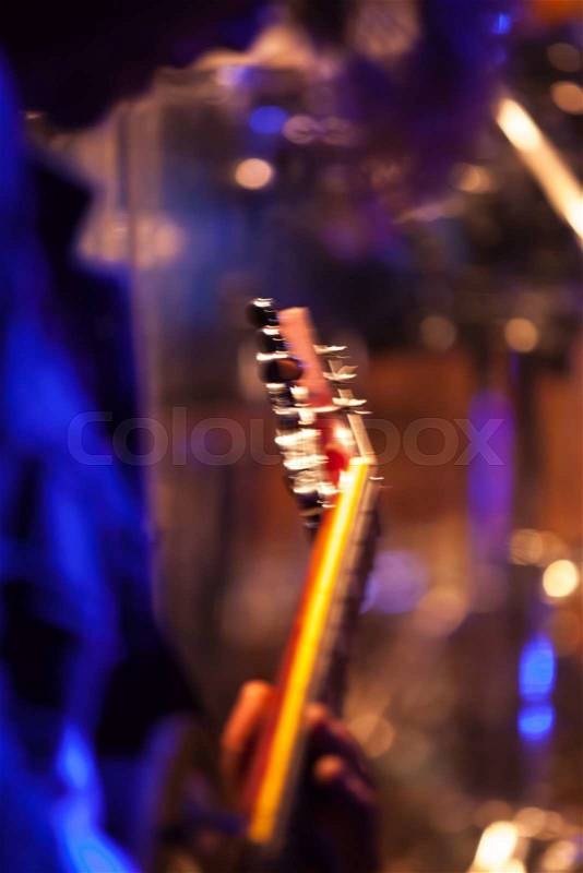 Colorful blurred rock music vertical background, guitar player on a stage with colorful illumination, stock photo