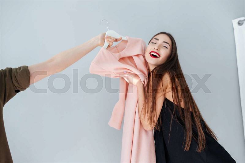 Cheerful woman hugging dress in clothing store , stock photo