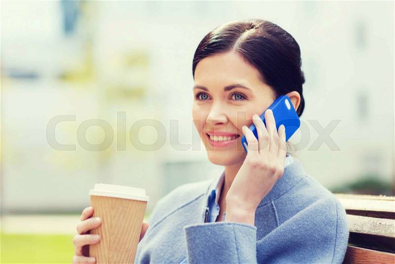 Business and people concept - young smiling woman calling on smartphone and drinking coffee in city, stock photo