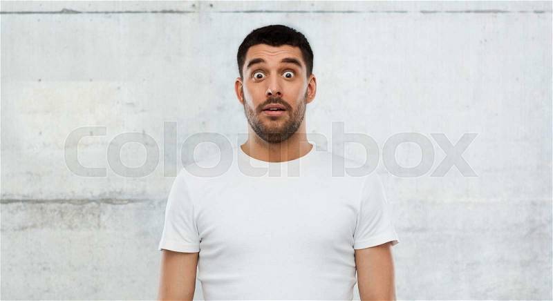 Emotion, advertisement and people concept - scared man in white t-shirt over gray wall background, stock photo