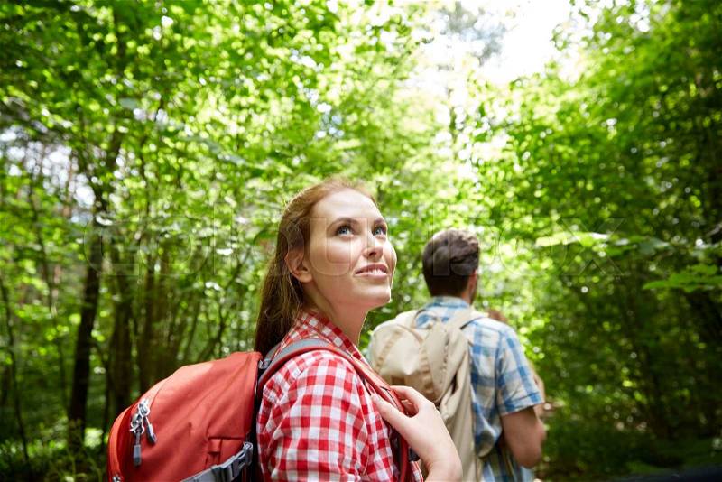 Adventure, travel, tourism, hike and people concept - group of smiling friends walking with backpacks in woods, stock photo