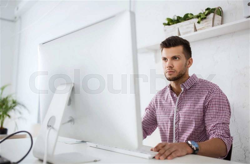 Business, technology, education and people concept - young creative man or student with computer at office, stock photo