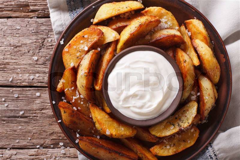 Spicy potato wedges with herbs and mayonnaise on a plate closeup. Horizontal view from above , stock photo