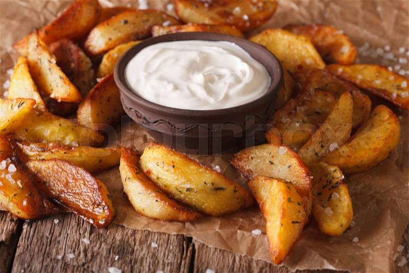 Baked potato wedges and sauce close-up on the table. horizontal, rustic