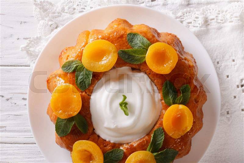 French pastries: Savarin with decorated apricots and mint close-up on a plate. Horizontal view from above , stock photo