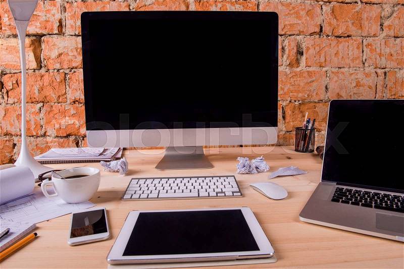 Desk with various gadgets and office supplies. Computer, smart phone, tablet and other devices and stationery around the workplace, stock photo
