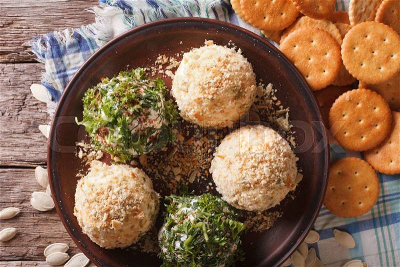 Healthy snacks: Cheese balls with crackers, herbs and pumpkin seeds close-up on a plate. horizontal view from above , stock photo