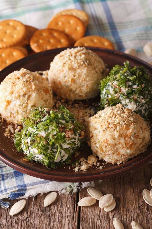Curd cheese balls with crackers, herbs and pumpkin seeds macro on a plate. Vertical\, stock photo