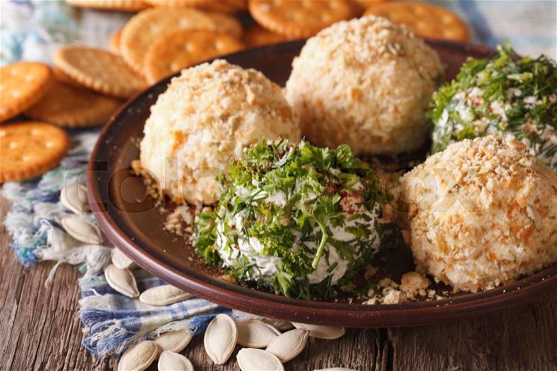 Healthy snacks: Cheese balls with crackers, herbs and pumpkin seeds close-up on a plate. horizontal , stock photo
