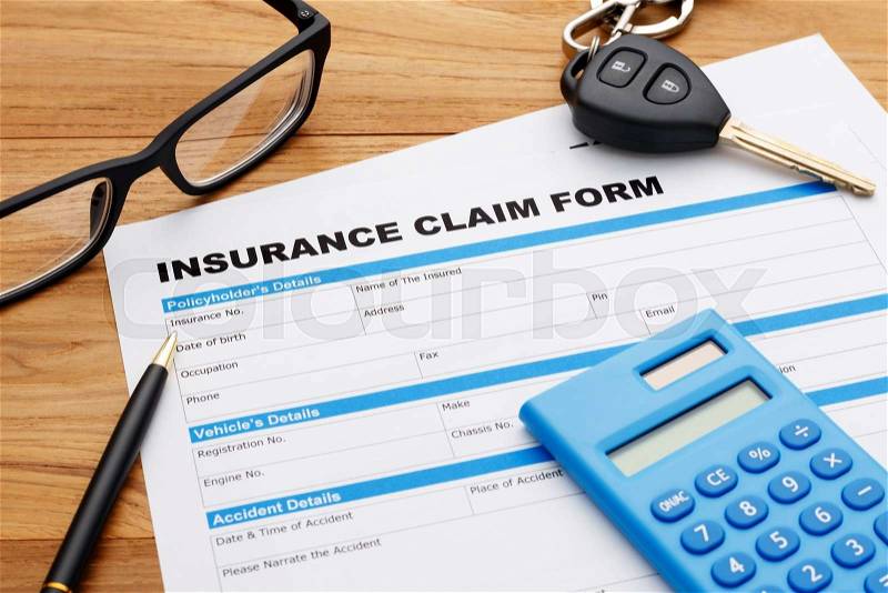 Car insurance claim form with pen and car key on wood desk, stock photo