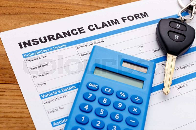 Car insurance claim form with car key and calculator on wood desk, stock photo