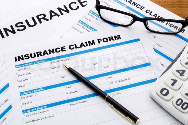 Insurance claim form with pen and calculator on wood desk, stock photo