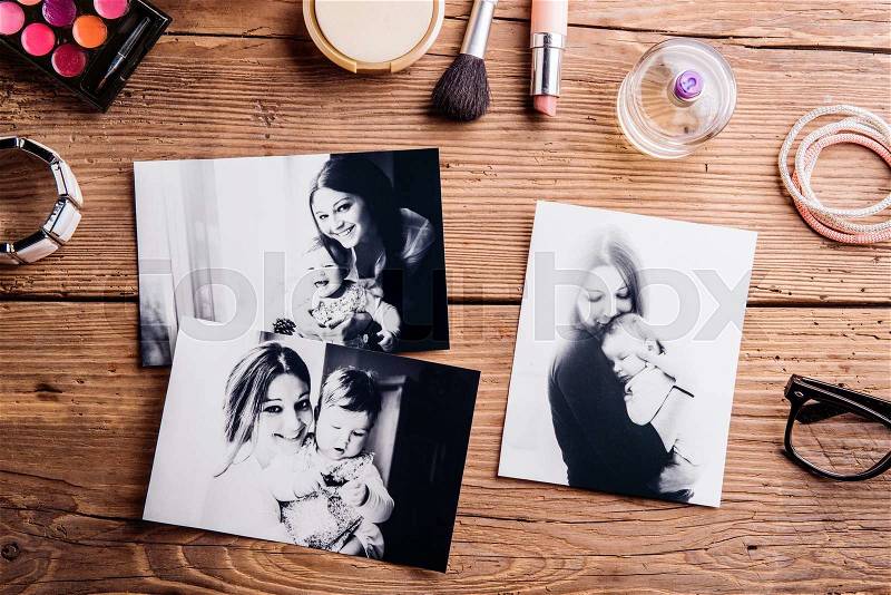 Mothers day composition. Black-and-white pictures of mother holding her little baby and various make up products. Studio shot on wooden background, stock photo