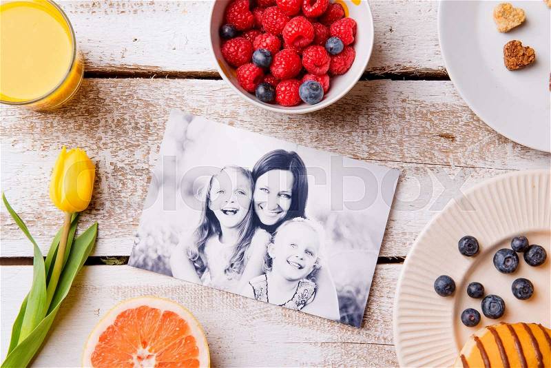 Mothers day composition. Black-and-white picture of mother with her daughters and a breakfast meal. Studio shot on wooden background, stock photo