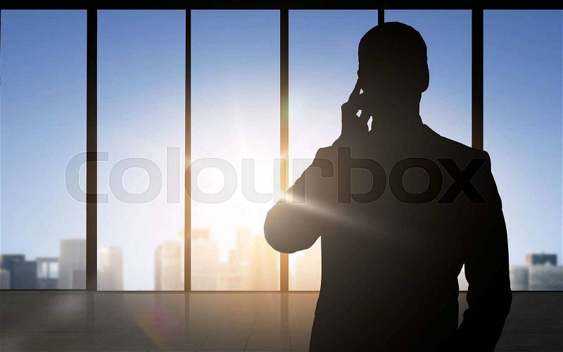 Business and people concept - silhouette of businessman calling on smartphone over office window background, stock photo