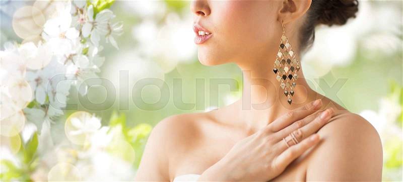 Glamour, beauty, jewelry and luxury concept - close up of beautiful woman with earrings over natural spring cherry blossom, stock photo