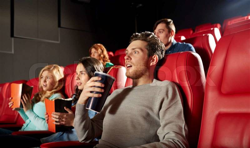 Cinema, entertainment and people concept - friends with popcorn and soda watching horror or thriller movie in theater, stock photo
