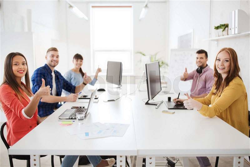Business, startup, success and people concept - creative team with computers, blueprint and scheme showing thumbs up at office, stock photo