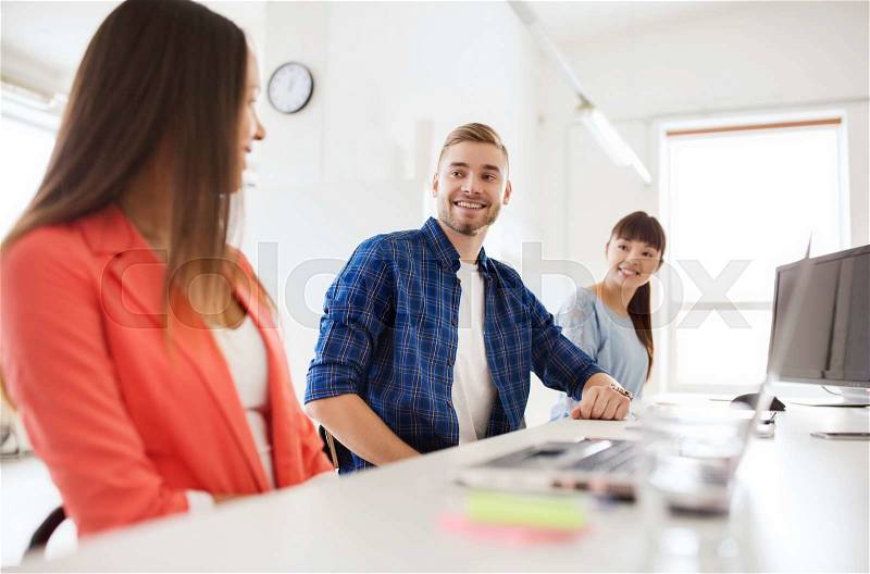 Business, communication, startup and people concept - happy multiracial creative team talking at office, stock photo