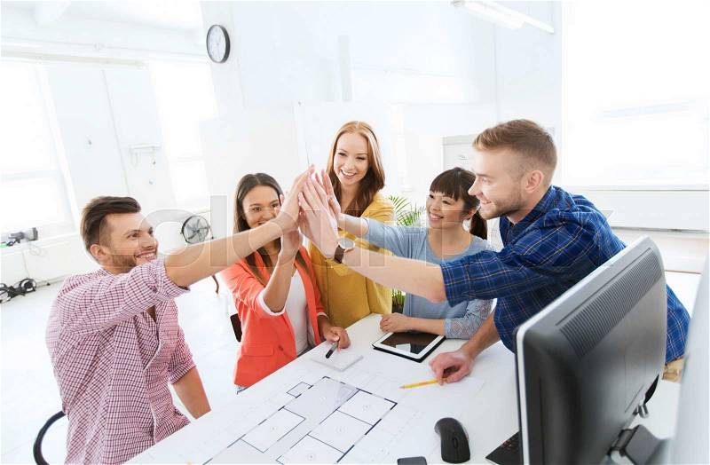 Business, startup, architecture, gesture and people concept - happy international creative architect team or students with blueprint making high five at office, stock photo