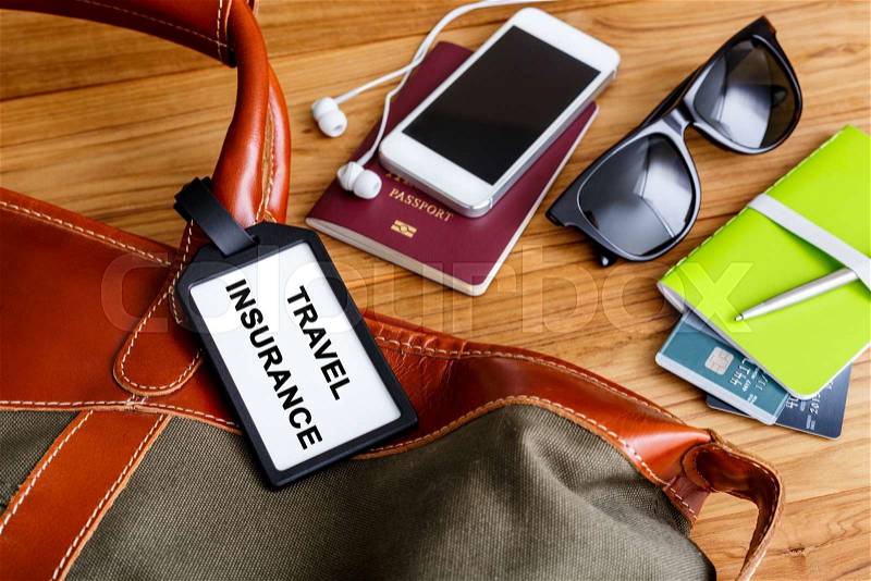 Travel bag with insurance tag and tourist accessories, stock photo