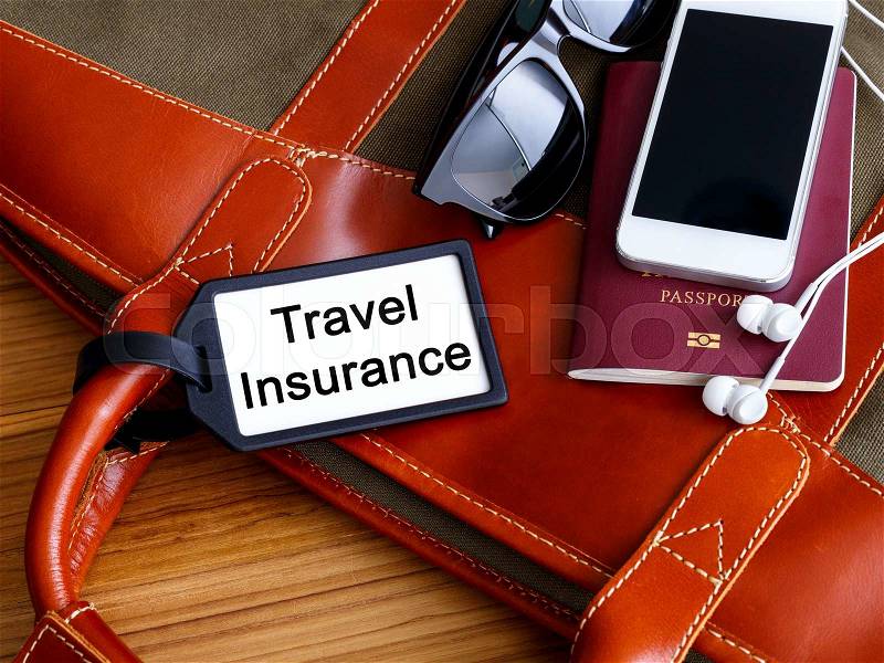 Travel bag with insurance tag passport phone and sunglasses, stock photo