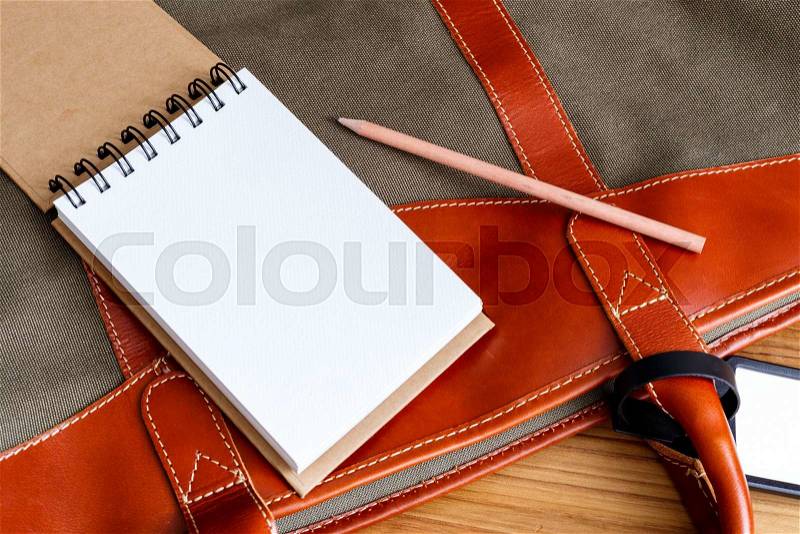 Travel planning concept with travel bag and notebook with pencil, stock photo