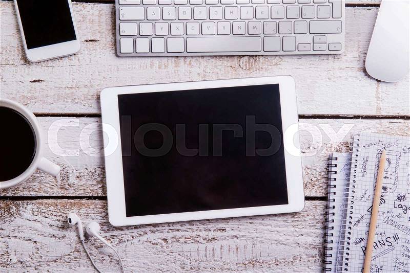Desk with gadgets and office supplies. Computer keyboard, smart phone, tablet and notepads around the workplace. Flat lay. Studio shot on white wooden background. Copy space, stock photo