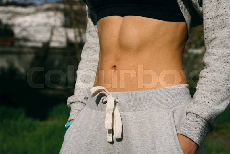 Belly athletic girl who is dressed in pants and a sports bra, stock photo