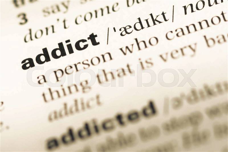 Close up of old English dictionary page with word addict, stock photo