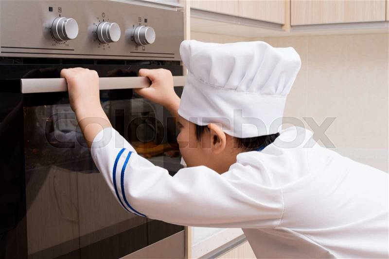 Asian Chinese Boy in white chef uniform Baking Cookies at Home, stock photo