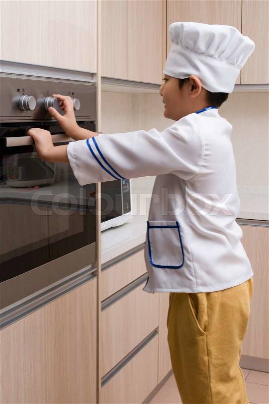 Asian Chinese Boy in white chef uniform Baking Cookies at Home, stock photo