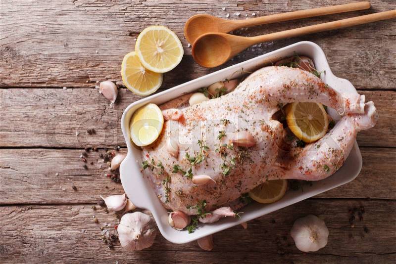 Raw chicken marinated with garlic, herbs, spices and lemon close up in a dish for baking. Horizontal view from above , stock photo