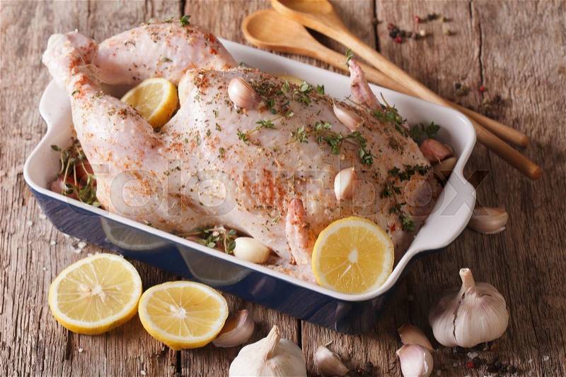 Raw whole chicken marinated with garlic, thyme and lemon close-up on the table. horizontal , stock photo