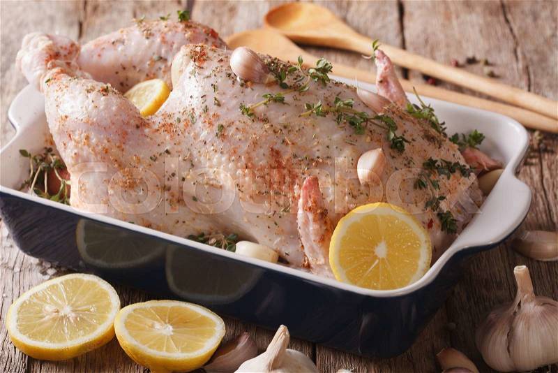 Raw whole chicken marinated with garlic, thyme and spices close up in baking dish on the table. horizontal , stock photo