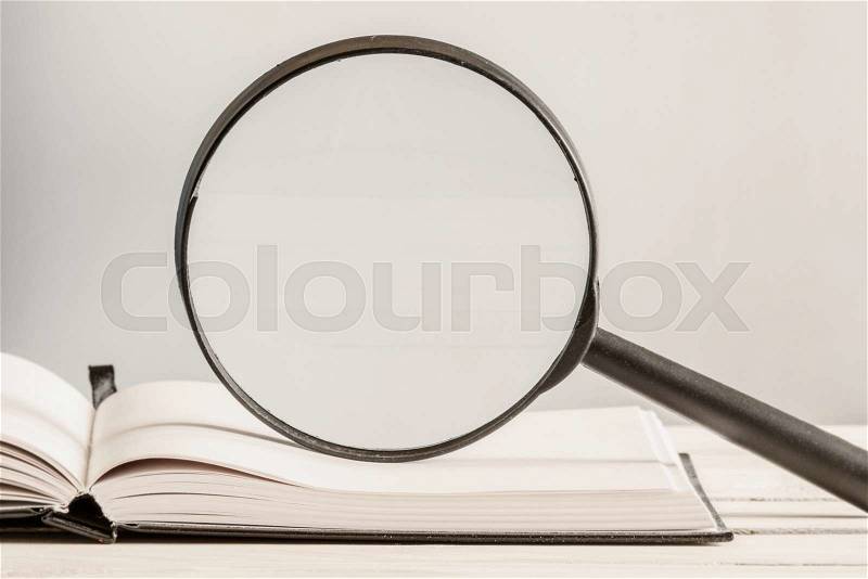 Text search in an open book with a magnifying glass, stock photo