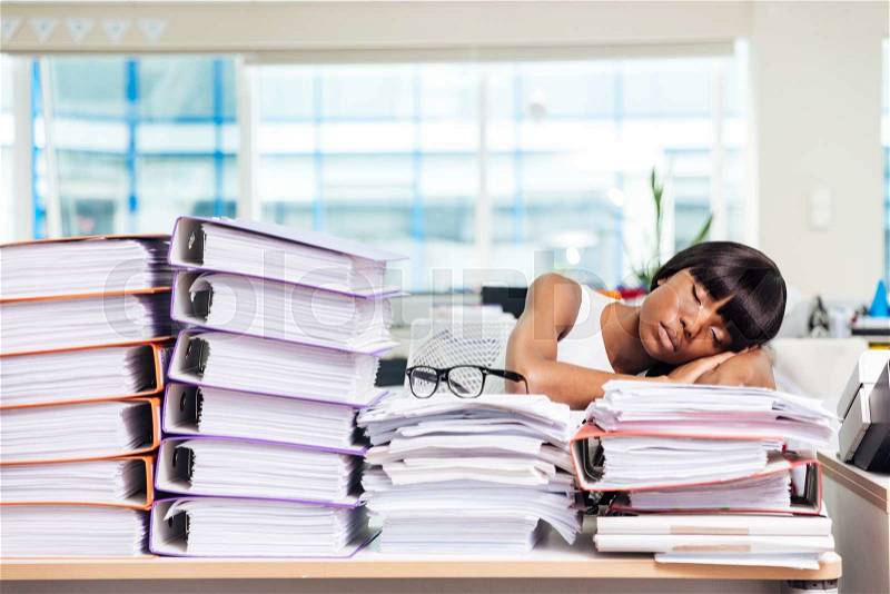 Afro american businesswoman sleeping on the papers in office, stock photo