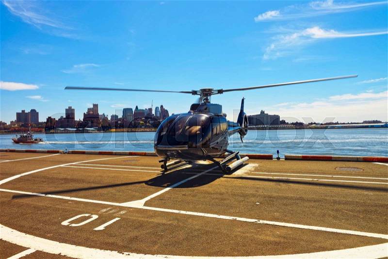 Black Helicopter on helipad in Lower Manhattan New York, USA, on East River. Pier 6. East River and skyscrapers on the background, stock photo