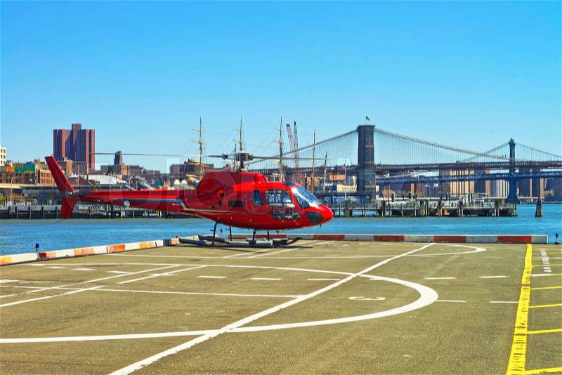 Helicopter taking off from helipad in Lower Manhattan New York, USA, on East River. Pier 6. Brooklyn Bridge and Manhattan Bridge on the background, stock photo