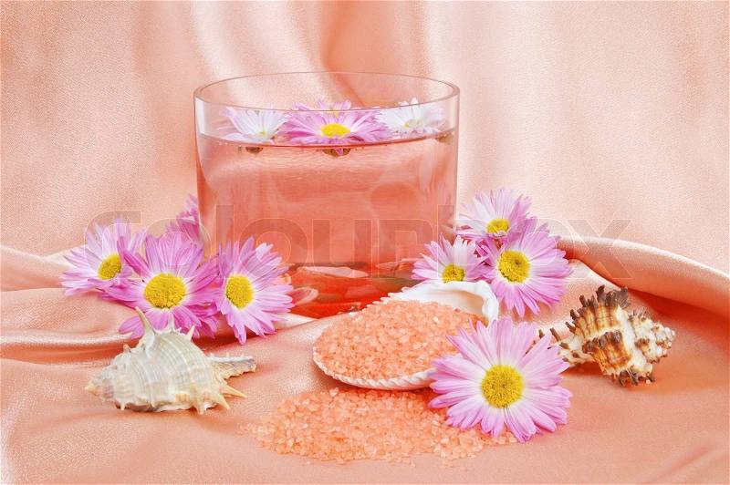 A bright pink spa and body care background. Salt and flower floating in glass bowl, stock photo