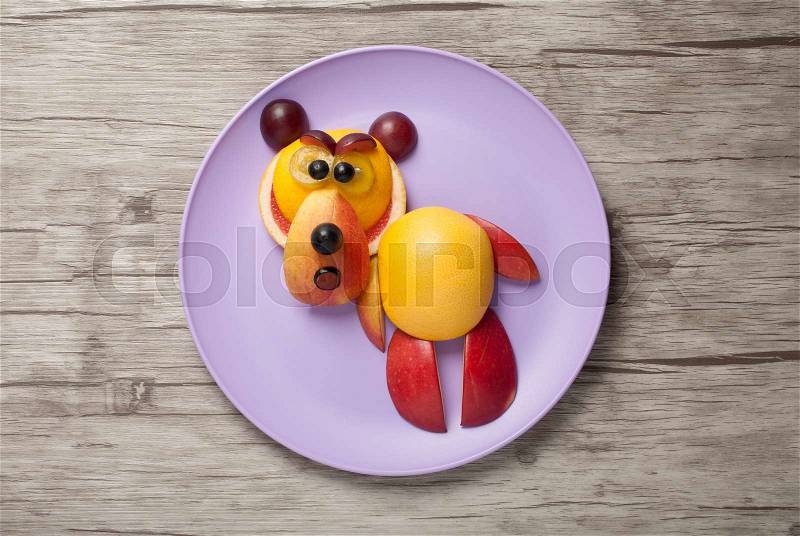 Bear made of fresh fruits on plate and wood, stock photo