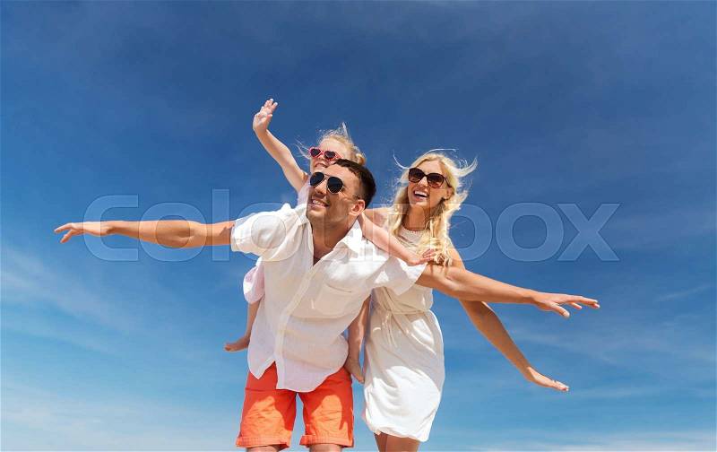 Family, summer vacation, adoption and people concept - happy man, woman and little girl in sunglasses having fun over blue sky background, stock photo