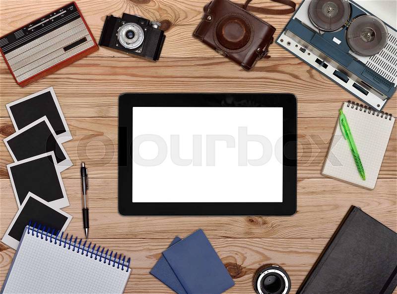 Retro reel tape recorder, vintage radio, retro camera on wooden table. Blank touch pad with white screen, stock photo